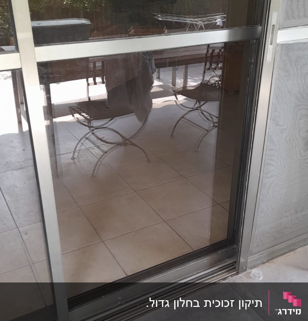 דלת זכוכית עם מסגרת מתכת, משתקפת חצר